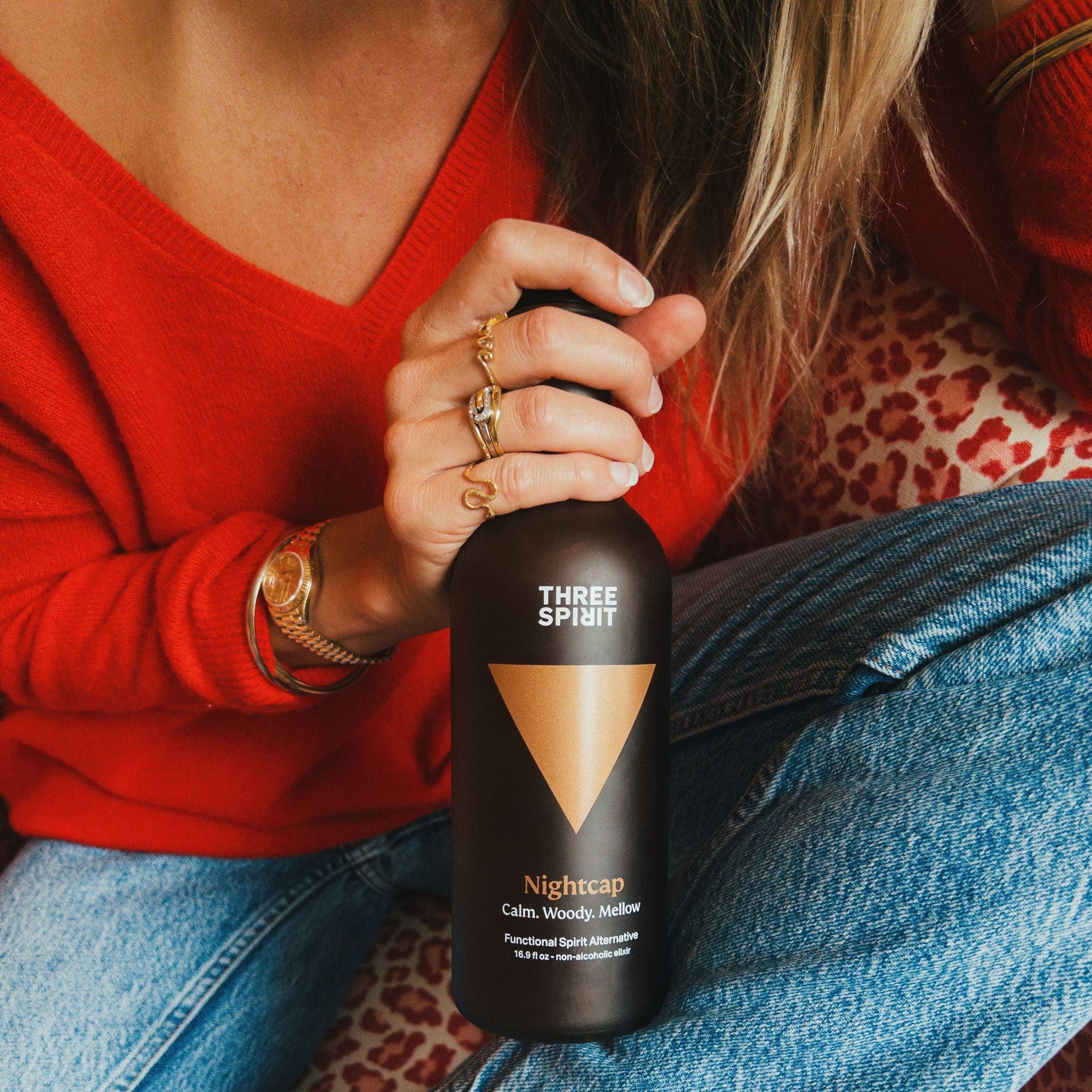 Een vrouw die een fles Three Spirit Nightcap in haar handen heeft. Een vrouw die een fles Three Spirit Nightcap in haar handen heeft.