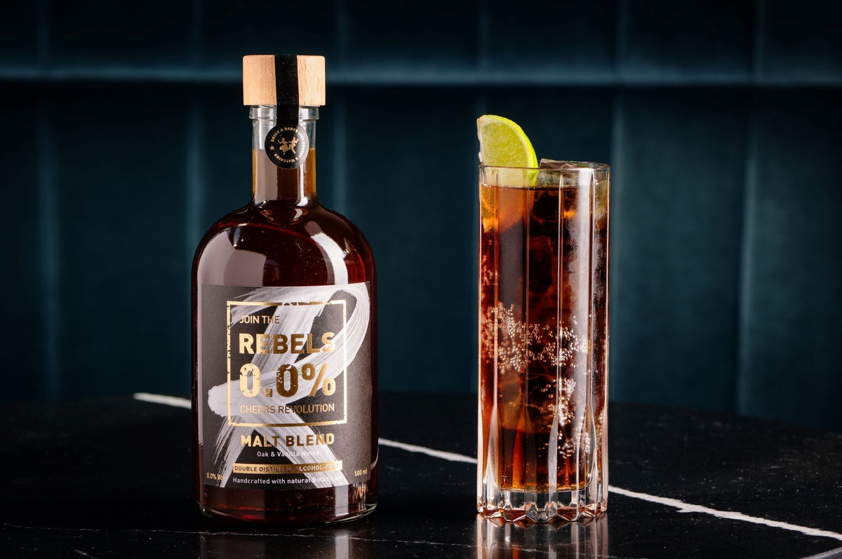 Fles Rebels 0.0% malt blend en glas alcoholvrije cocktail met limoen op marmeren tafel | World of NIX