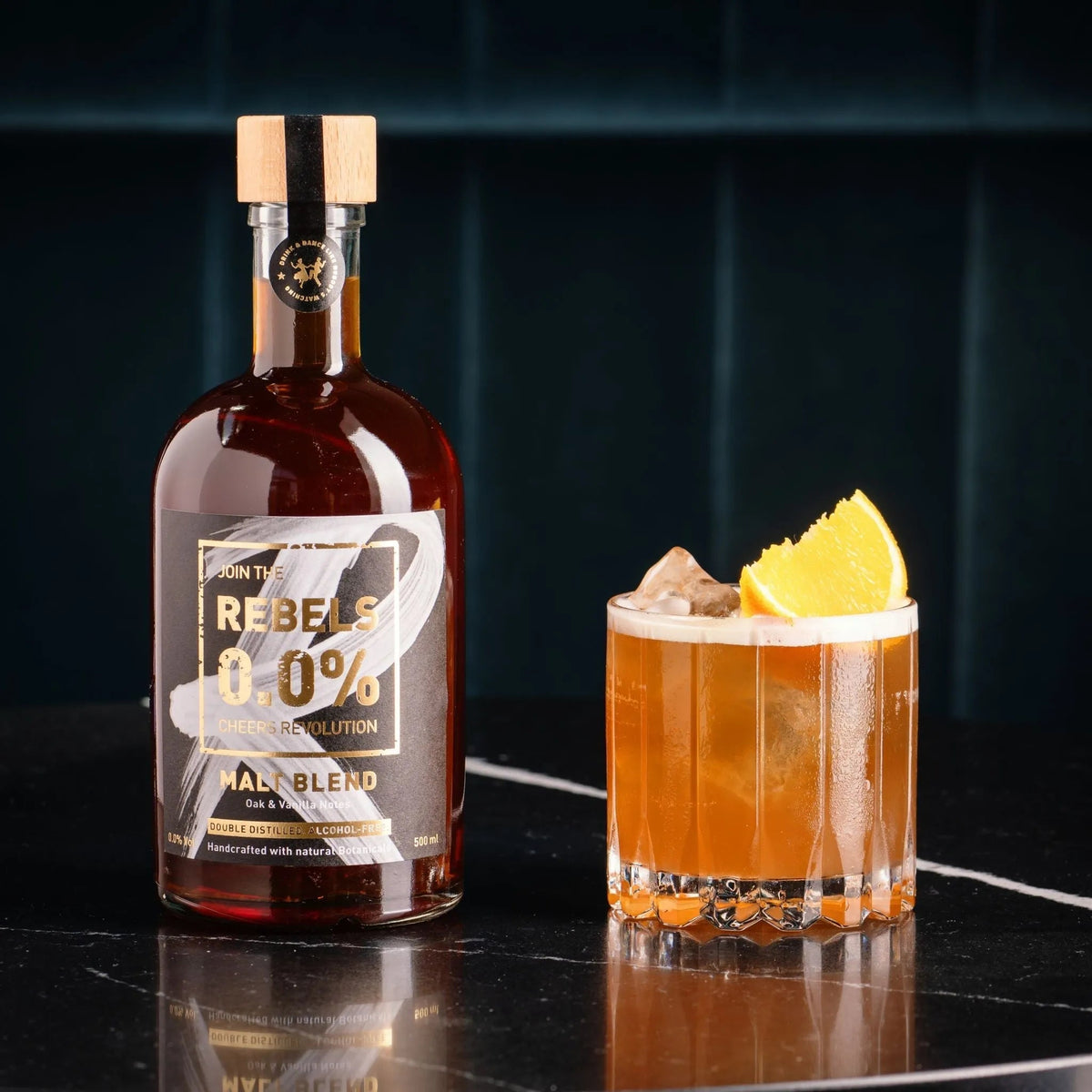 Fles Rebels 0.0% Malt Blend en alcoholvrije cocktail met sinaasappel op zwarte tafel | World of NIX
