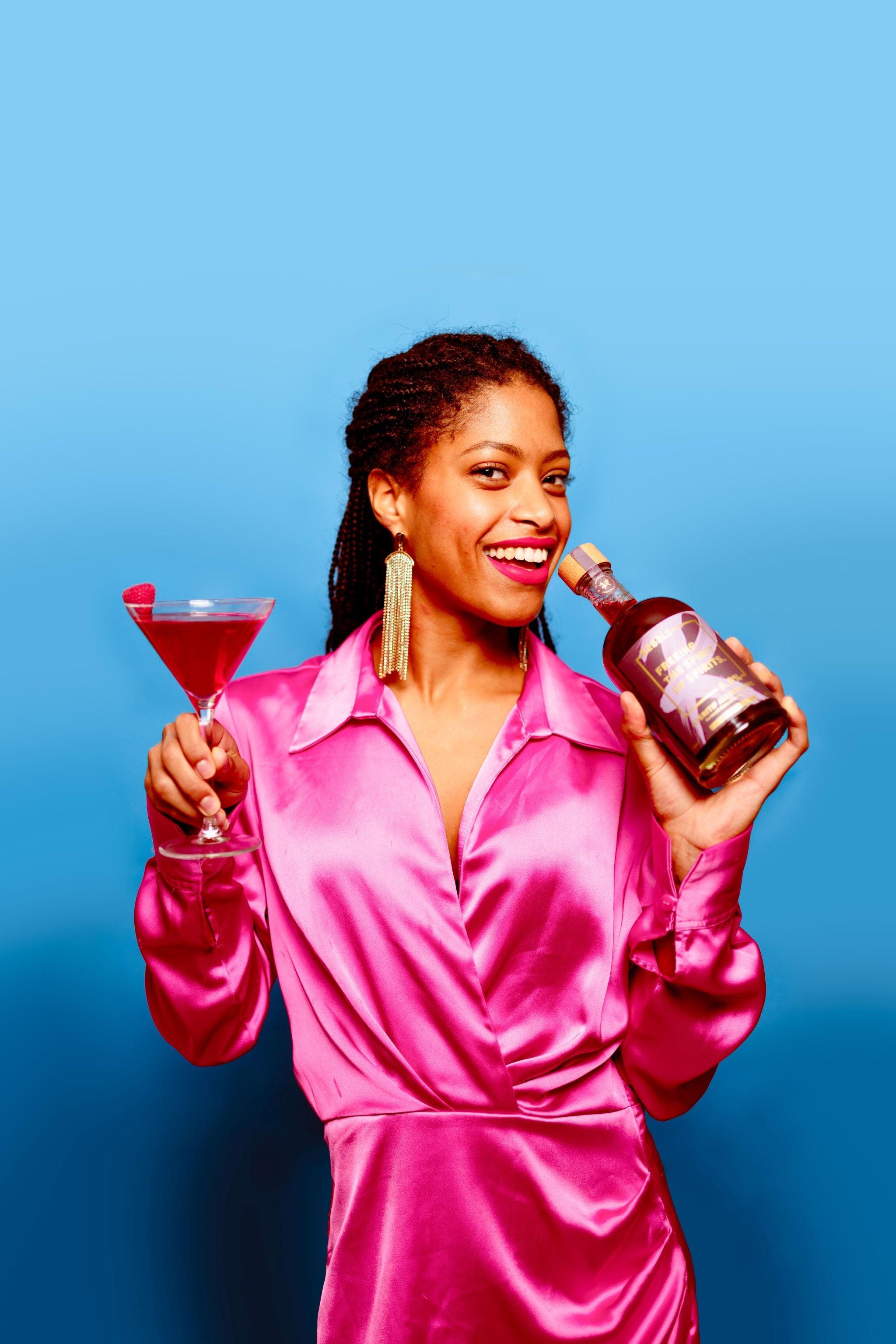 Vrouw in felroze jurk met alcoholvrije spirit en cocktail voor blauwe achtergrond | World of NIX
