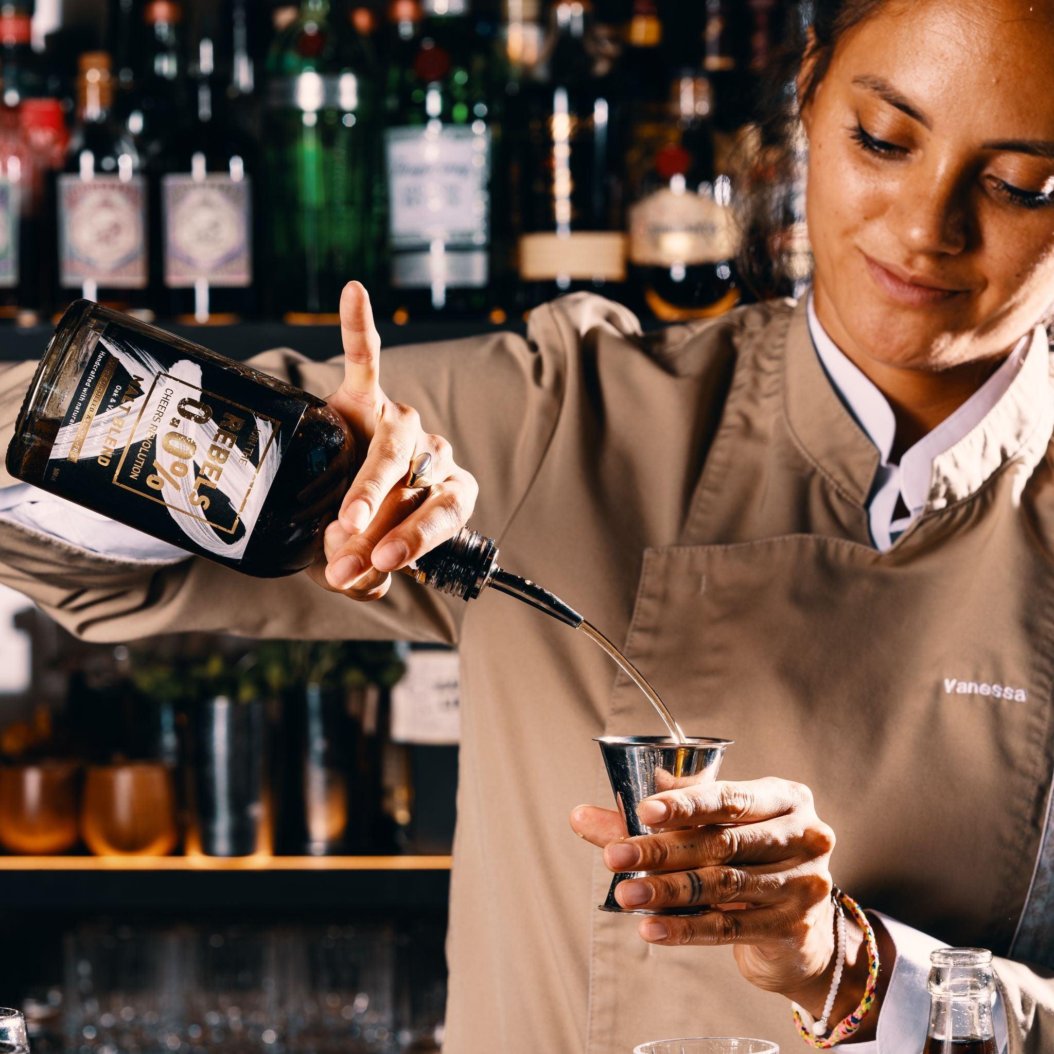 Bartender schenkt alcoholvrije Rebels 0.0 spirit in jigger, bar setting | World of NIX