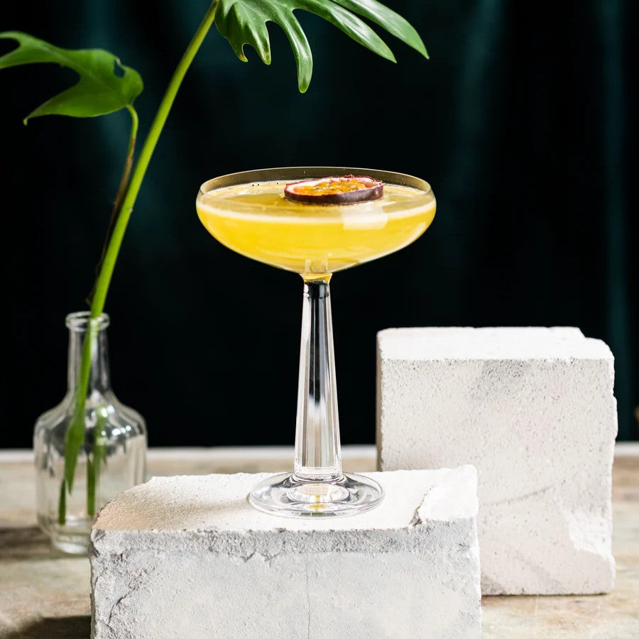 Alcoholvrije Yuzu Pornstar Martini in cocktailglas met passievrucht, moderne setting | World of NIX