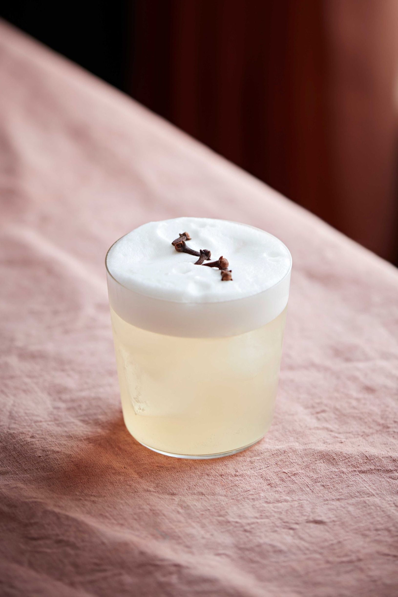 Alcoholvrije cocktail met schuim en kruidnagel garnering op roze tafelkleed | World of NIX