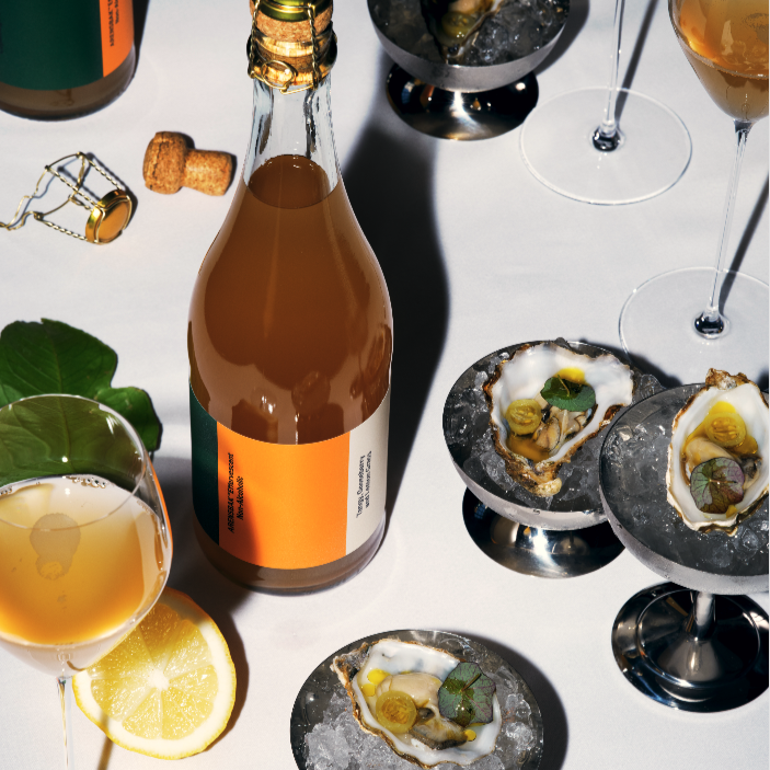 Fles alcoholvrije sparkling tea met oesters op ijs en citroen op witte tafel | World of NIX