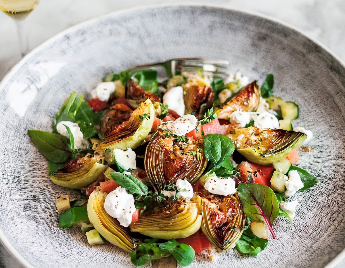 Salade met gegrilde artisjok, venkel, feta en verse kruiden op een lichtgrijs bord | World of NIX