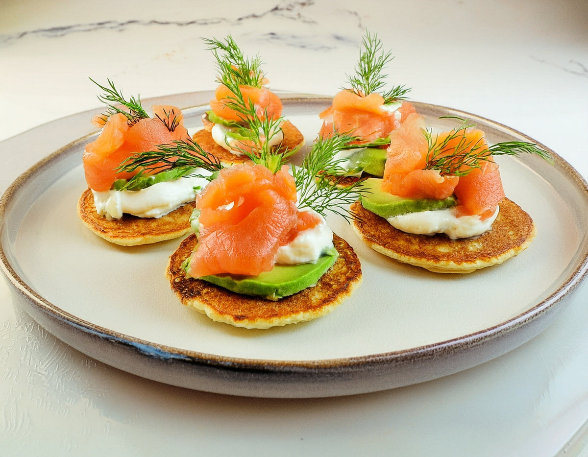 Blini met zalm, komkommer, roomkaas en dille op bord, luxe borrelhapje | World of NIX