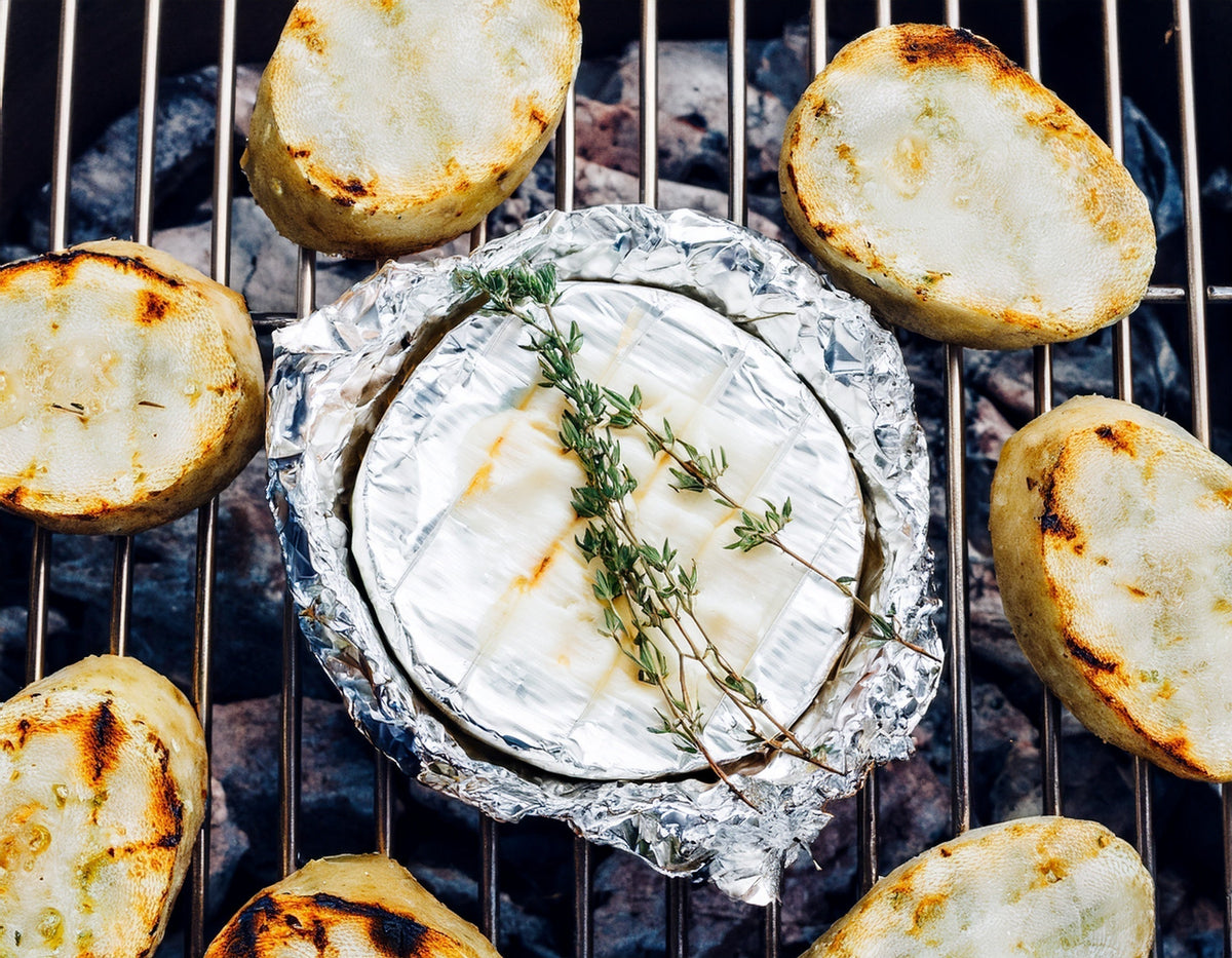 Gegrilde camembert met verse kruiden en aardappelschijfjes op barbecue grill | World of NIX