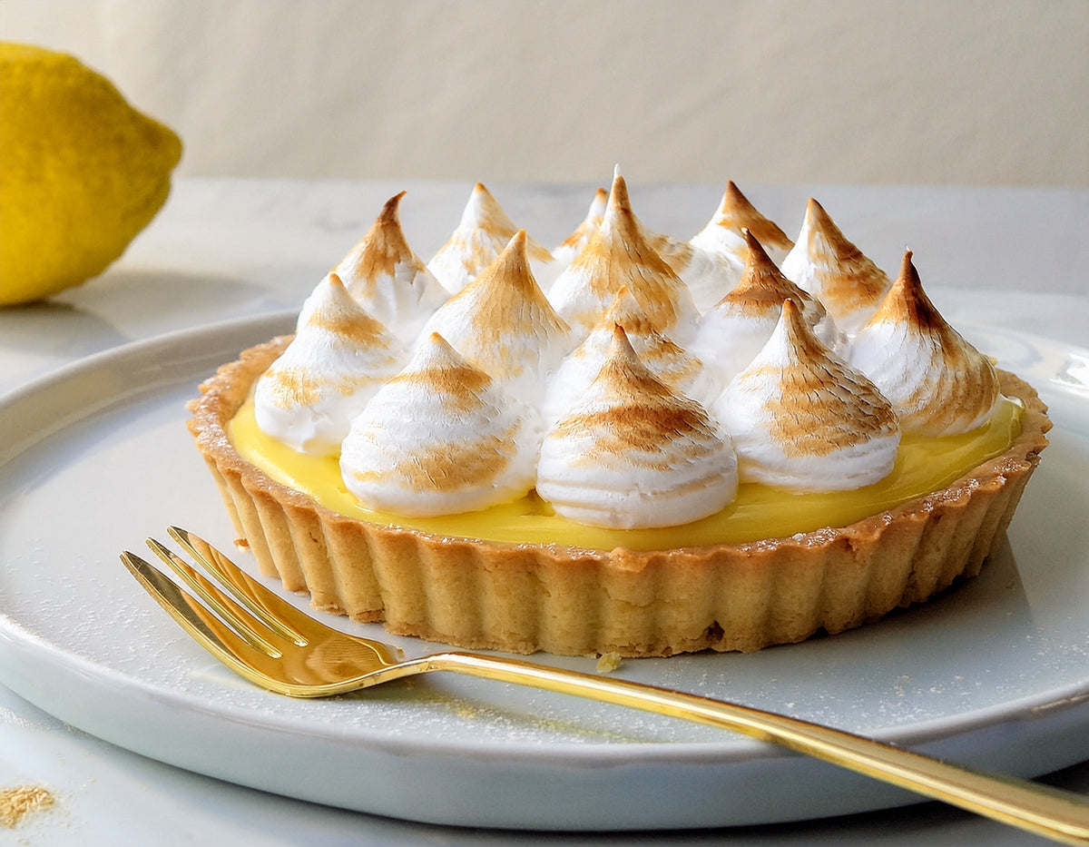 Citroen meringue taart met goudbruine toefjes op bord, citroen op achtergrond | World of NIX