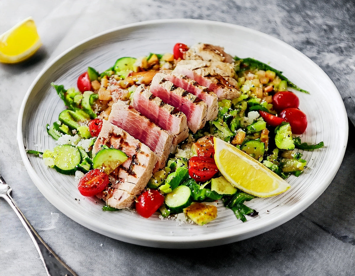 Gegrilde tonijn met bulgursalade, cherrytomaatjes en komkommer op een bord | World of NIX
