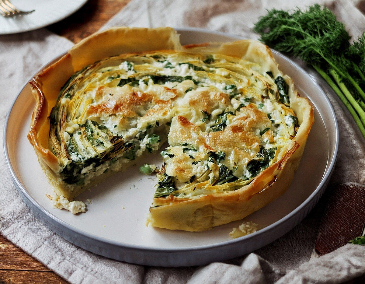 Hartige taart met spinazie, courgette, feta en dille op wit bord | World of NIX