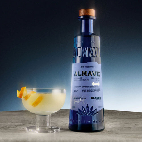 Blauwe fles alcoholvrije AlMave spirit met cocktail en sinaasappelschil op tafel | World of NIX