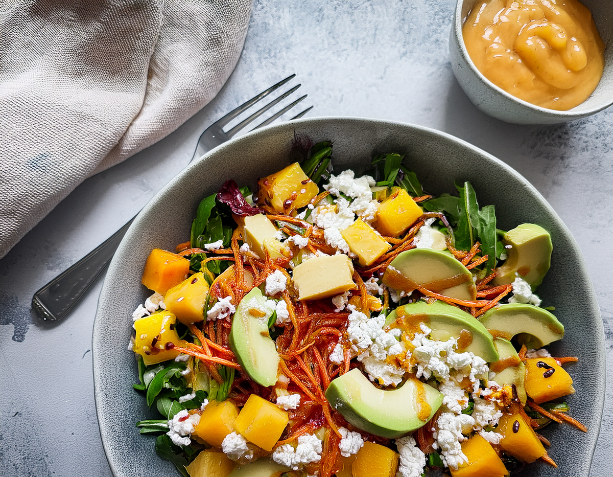 Frisse mangosalade met avocado, geitenkaas en wortel, geserveerd met dressing | World of NIX