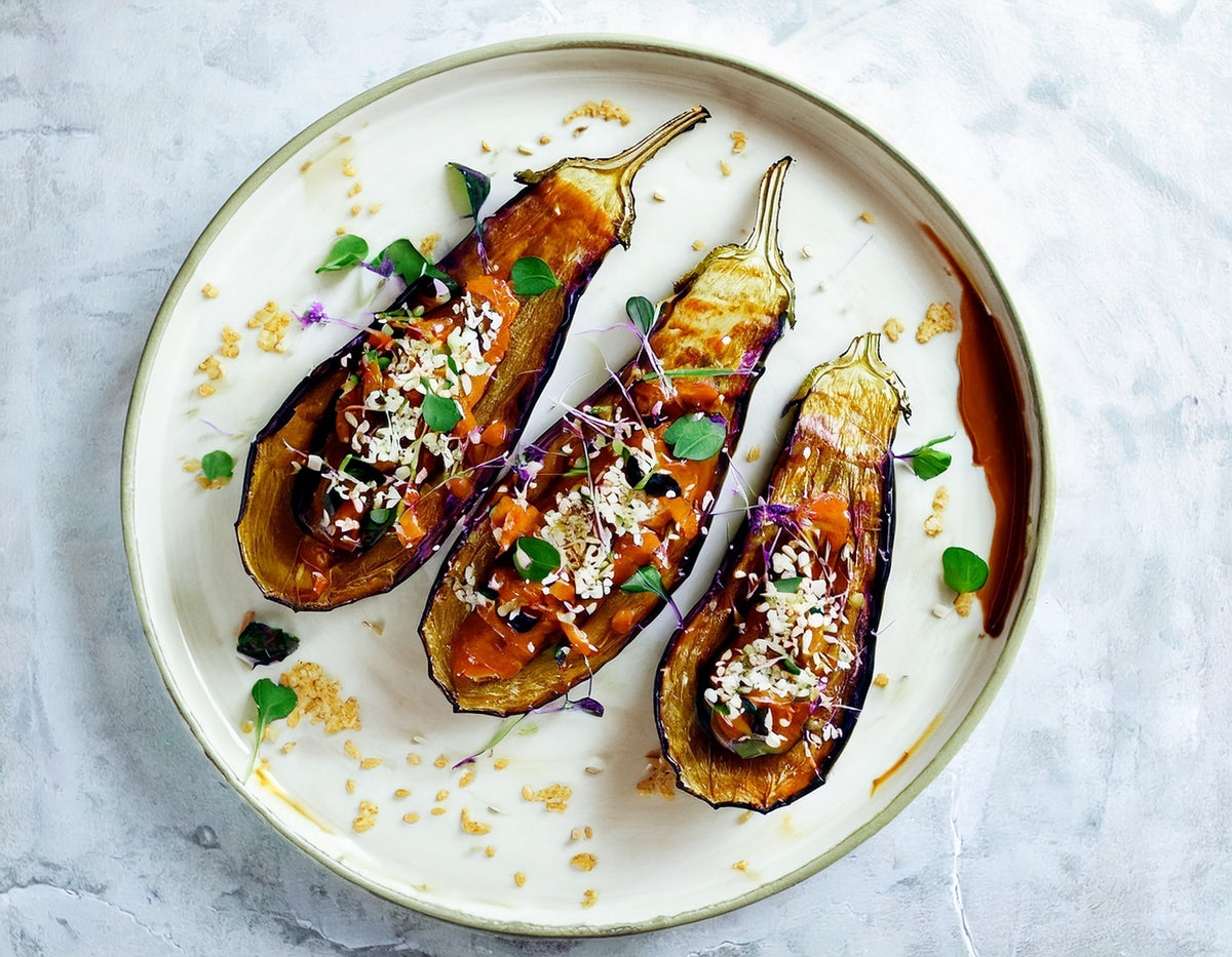 Gegrilde miso aubergine met sesam en verse kruiden op een witte schaal | World of NIX