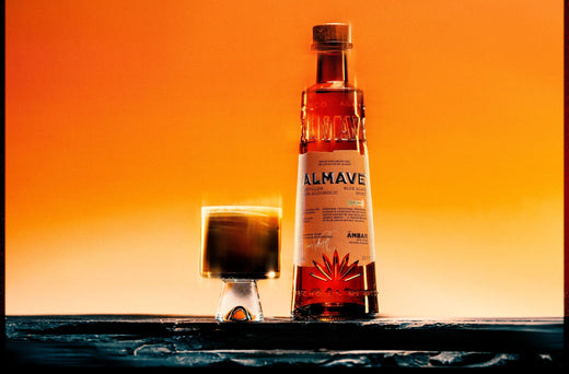 Fles Almave alcoholvrije spirit en glas cocktail op donkere tafel, oranje achtergrond | World of NIX