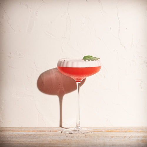 Alcoholvrije mocktail met schuimlaag en muntblad in cocktailglas op houten tafel | World of NIX