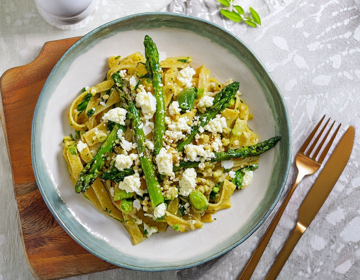 Bord tagliatelle pasta met groene asperges en feta kaas, bovenaanzicht | World of NIX