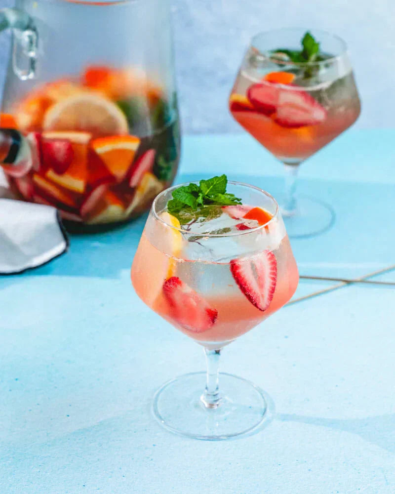 Glas alcoholvrije sangria met aardbei, citrus en munt op blauwe achtergrond | World of NIX