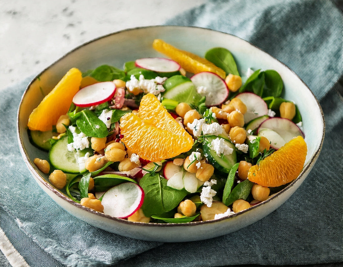 Verse salade met kikkererwten, sinaasappel, radijsjes en feta in kom op blauwe doek | World of NIX