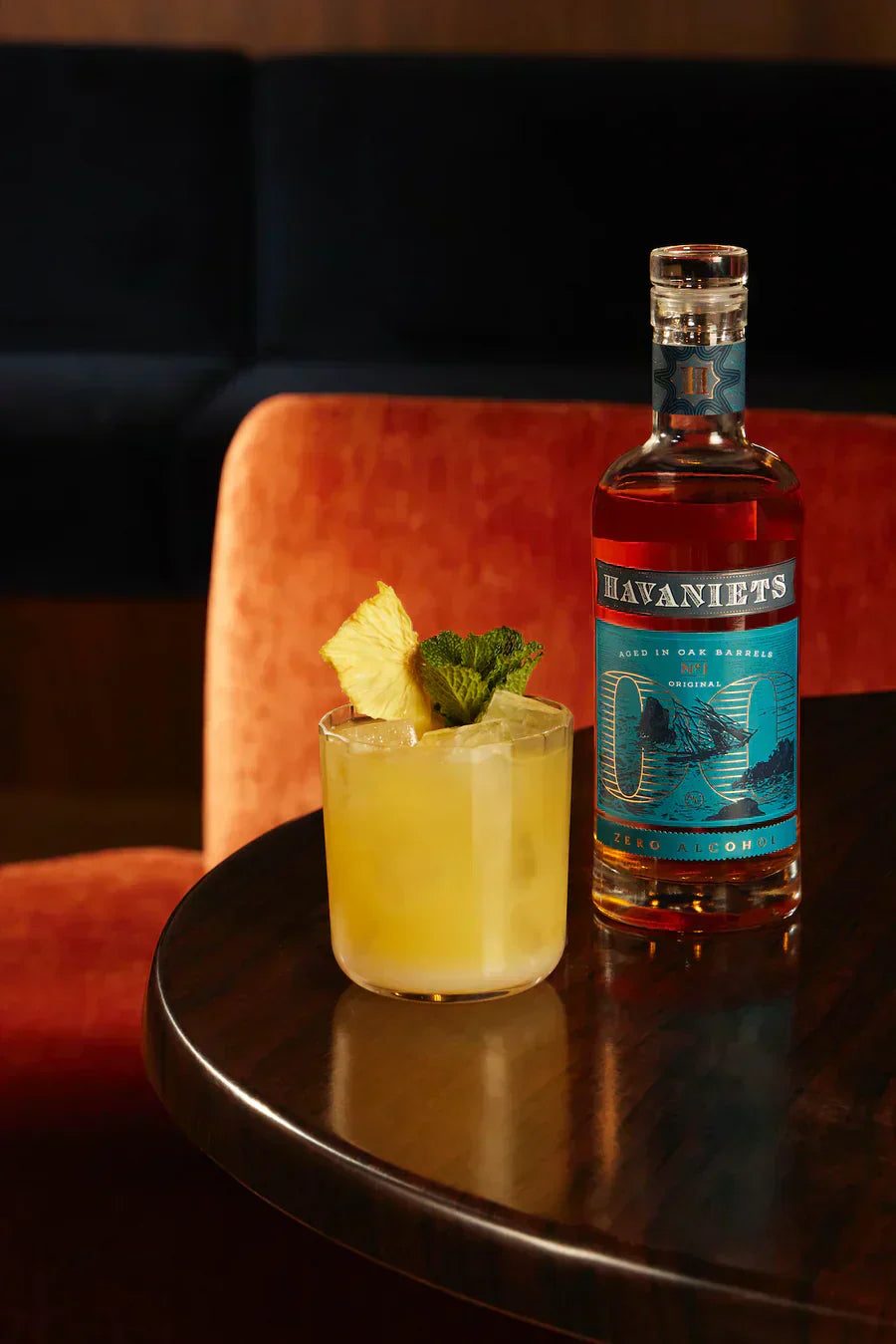 Fles Havaniets alcoholvrije spirit en gele cocktail met ananas en munt op tafel | World of NIX