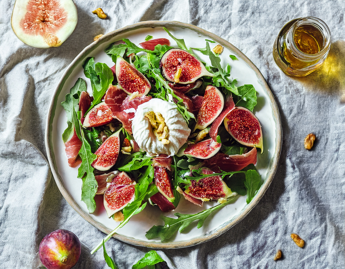 Verse vijgensalade met burrata, rucola, rauwe ham en walnoten op een bord | World of NIX