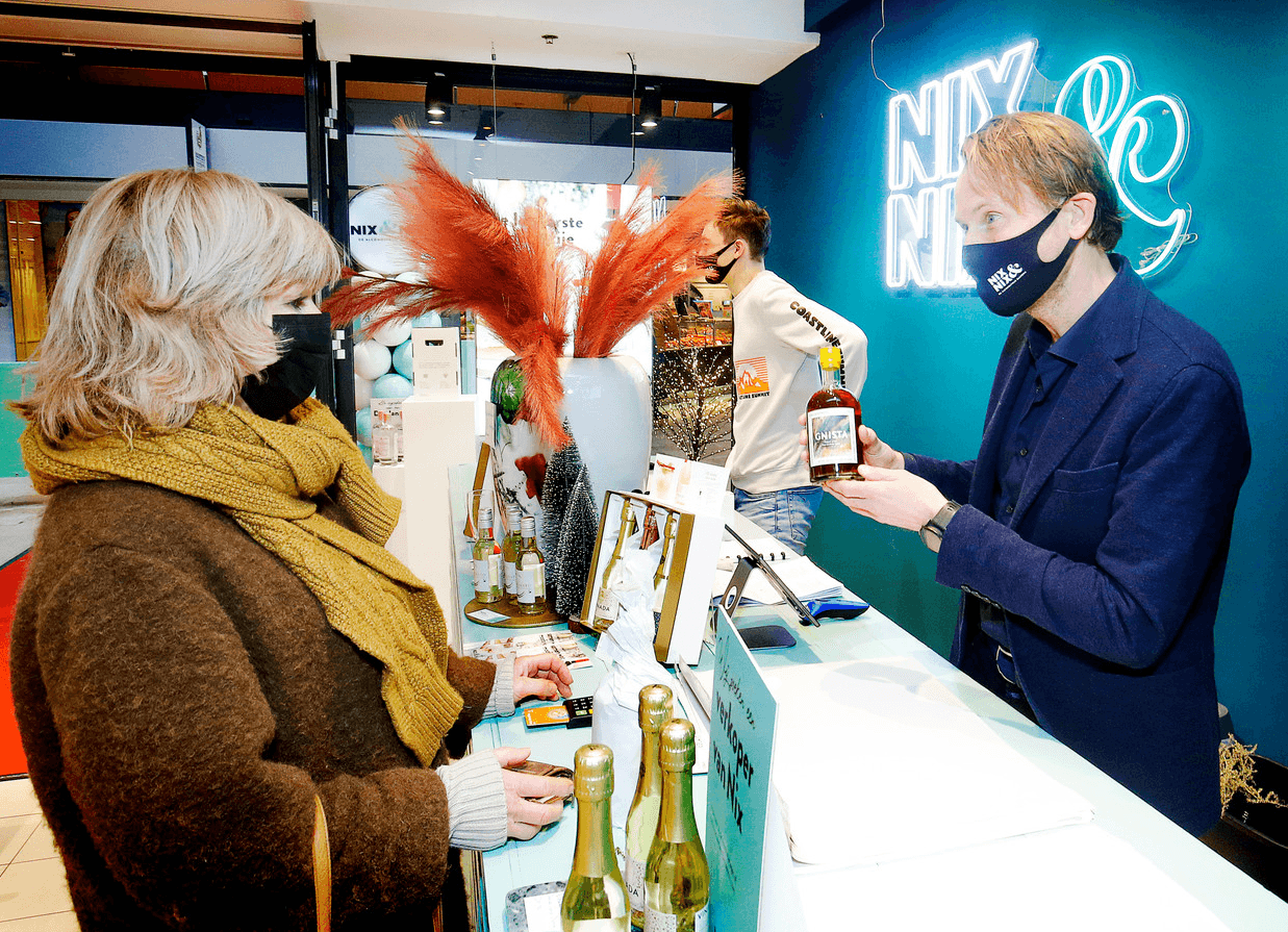 Medewerker toont alcoholvrije spirit aan klant in World of NIX winkel | World of NIX