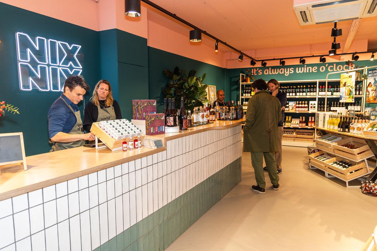 Interieur van alcoholvrije winkel met klanten aan toonbank, flessen en NIX NIX neonbord | World of NIX