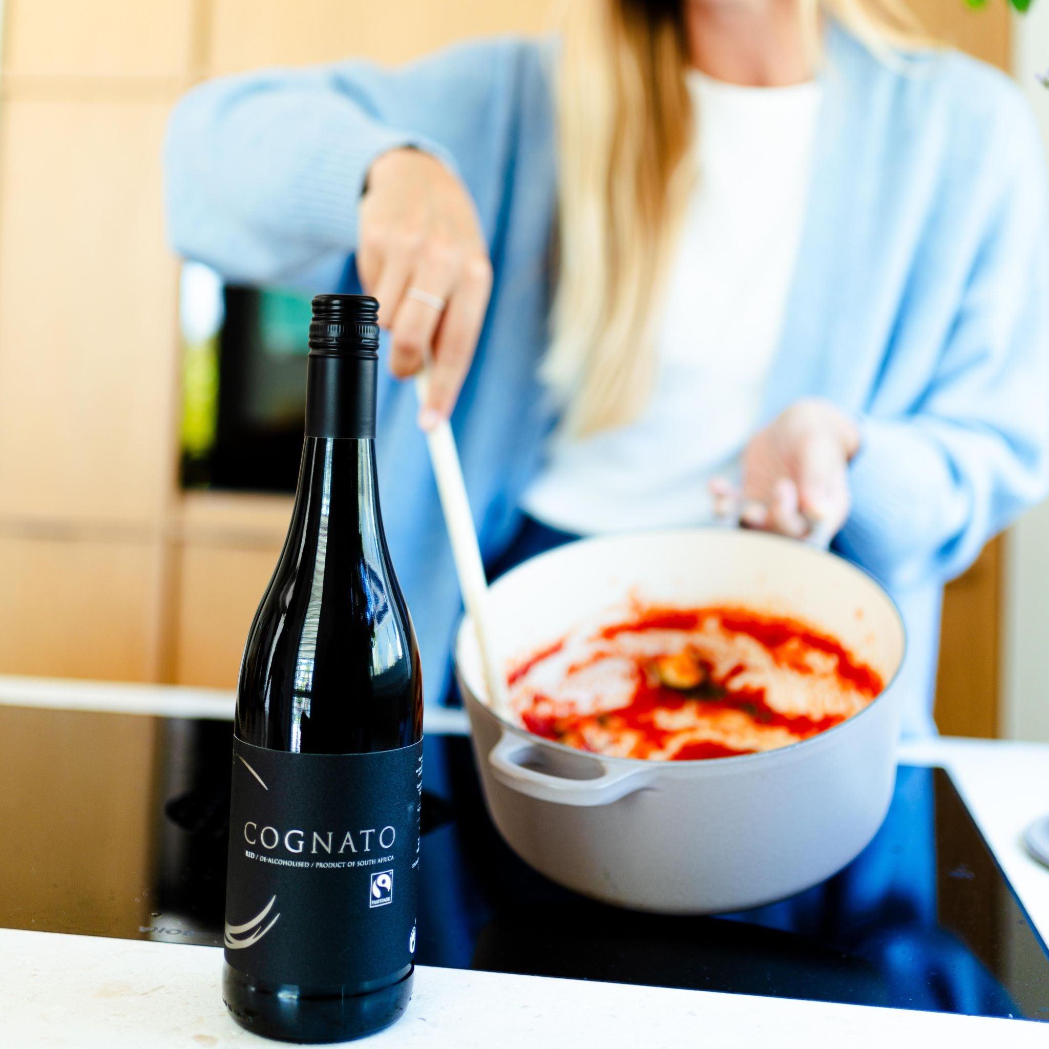 Fles Cognato alcoholvrije wijn op aanrecht, vrouw roert in pan tomatensaus | World of NIX