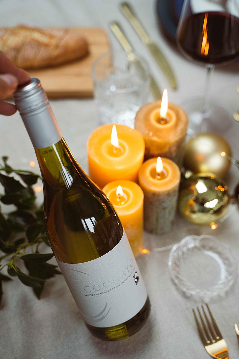 Alcoholvrije witte wijnfles op feestelijk gedekte tafel met kaarsen en glas | World of NIX
