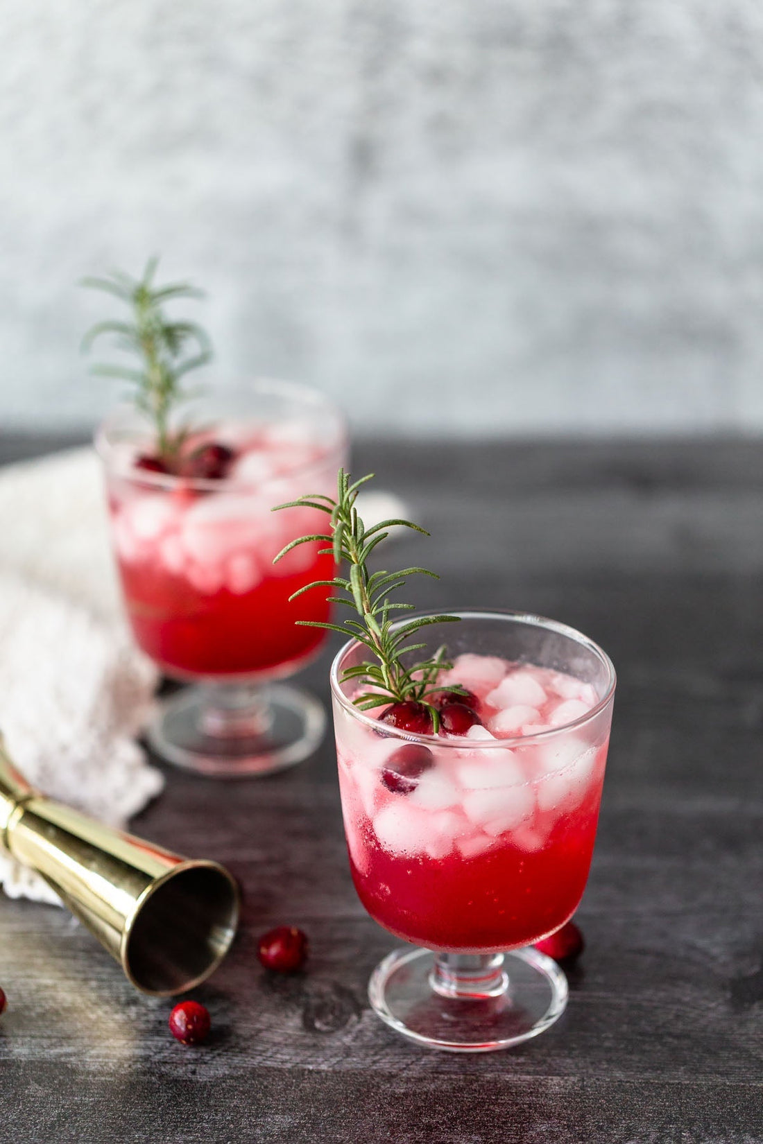 Twee cranberry-limoen mocktails met ijs, verse cranberries en rozemarijn op houten tafel | World of NIX