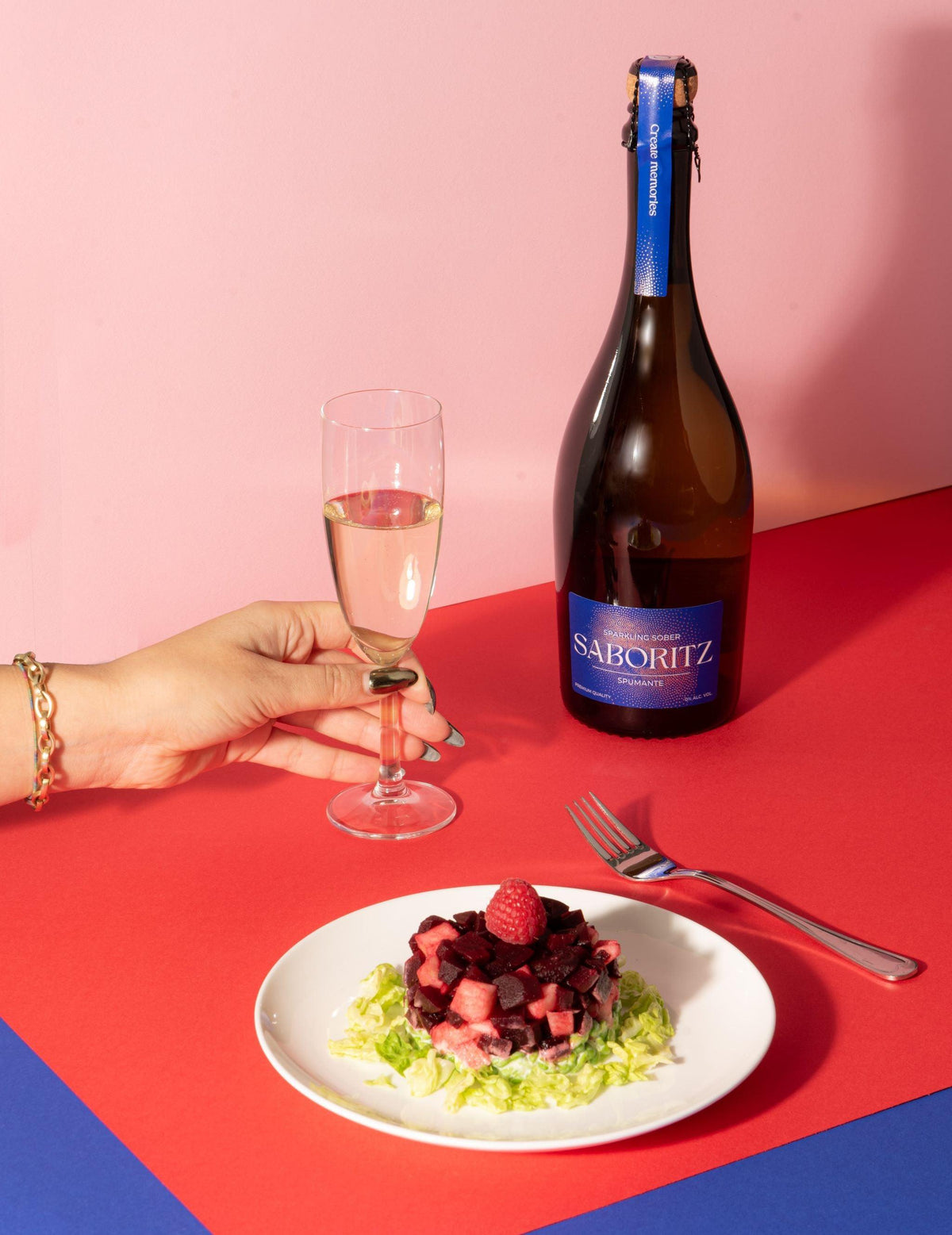 Alcoholvrije mousserende wijn Saboritz naast salade met framboos op gekleurde tafel | World of NIX