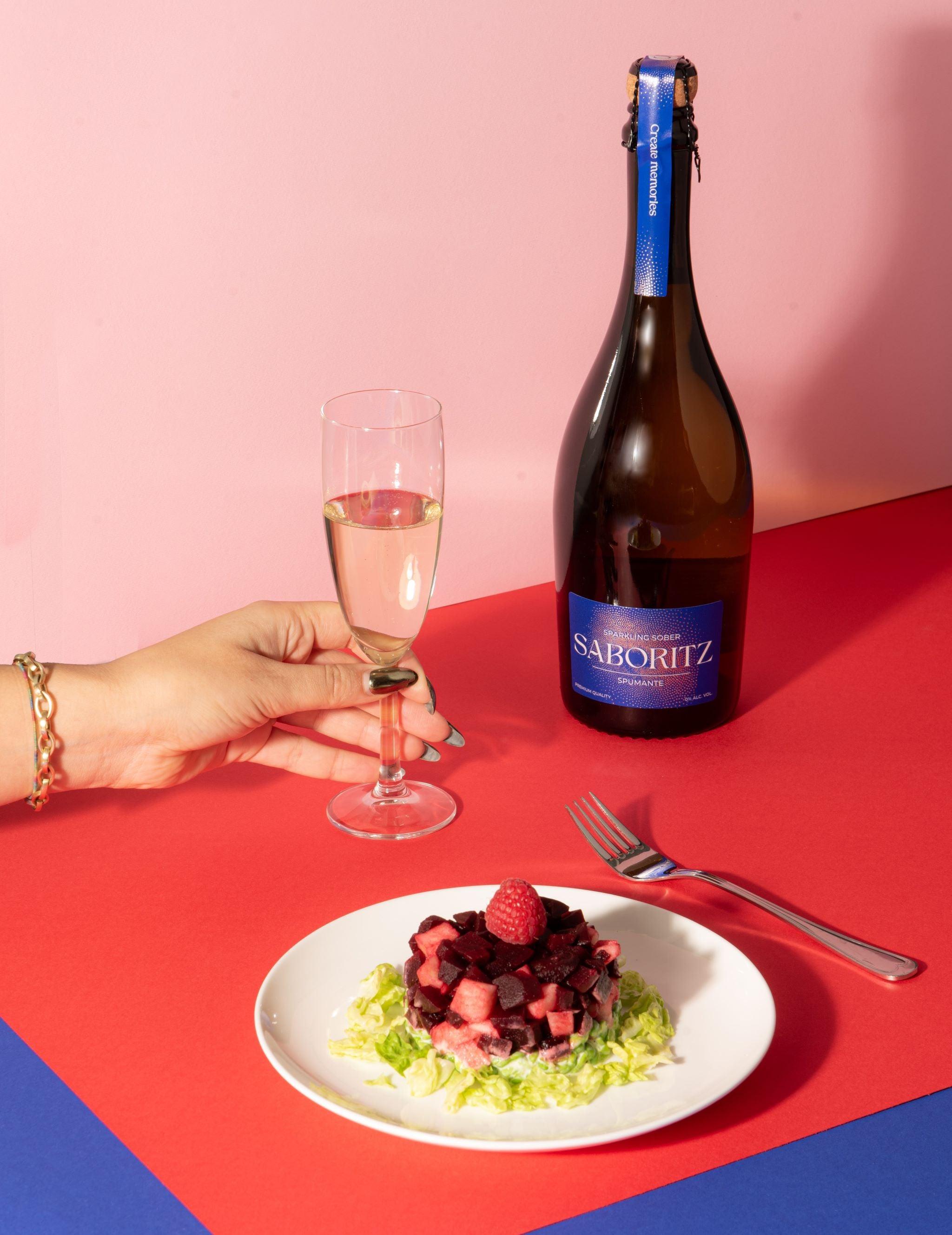 Alcoholvrije mousserende wijn Saboritz naast salade met framboos op gekleurde tafel | World of NIX