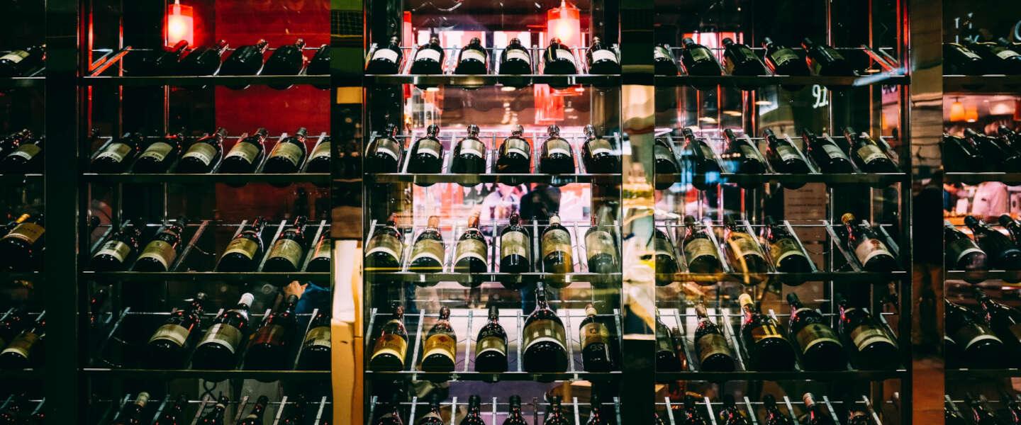 Wijnflessen opgestapeld in glazen rek in winkel, alcoholvrije wijnen selectie | World of NIX