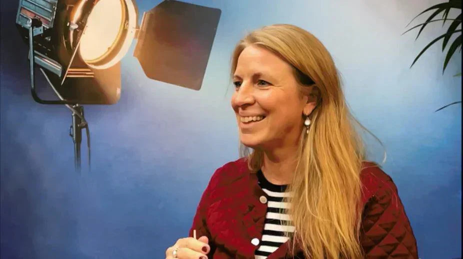 Vrouw met blond haar lacht voor blauwe achtergrond met studiolamp, World of NIX interview setting | World of NIX