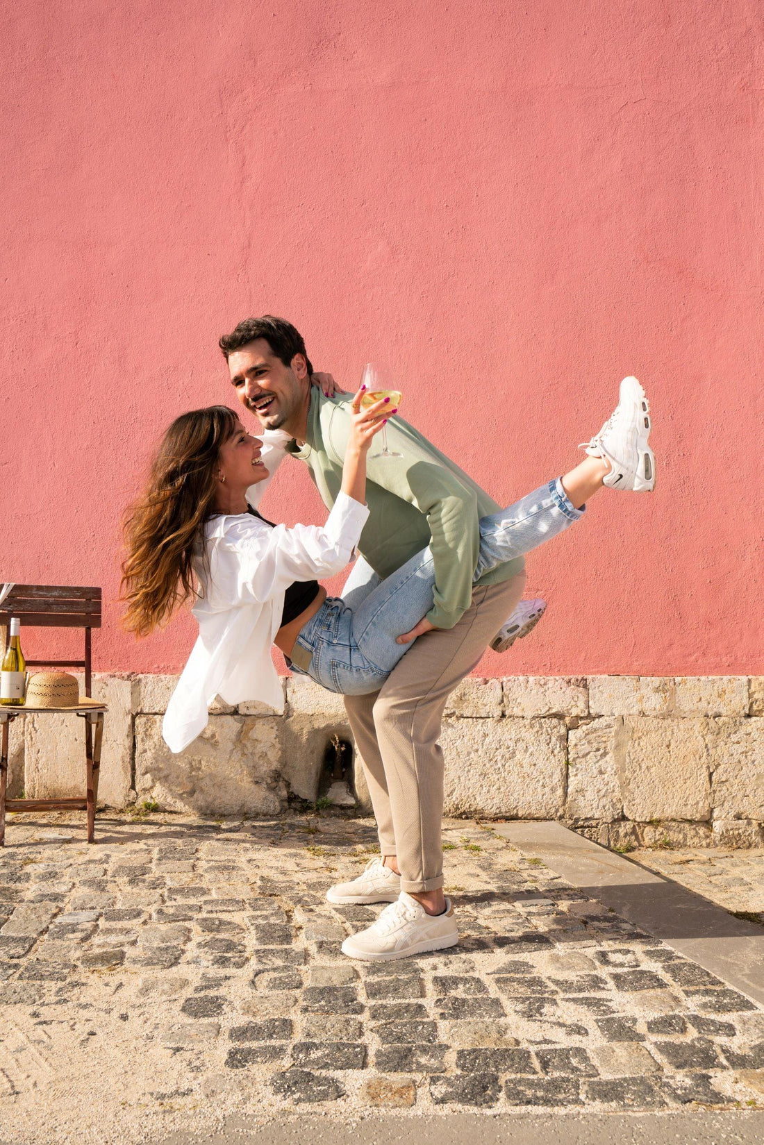 Lachend stel geniet van alcoholvrij drankje buiten tegen roze muur, zomerse sfeer | World of NIX