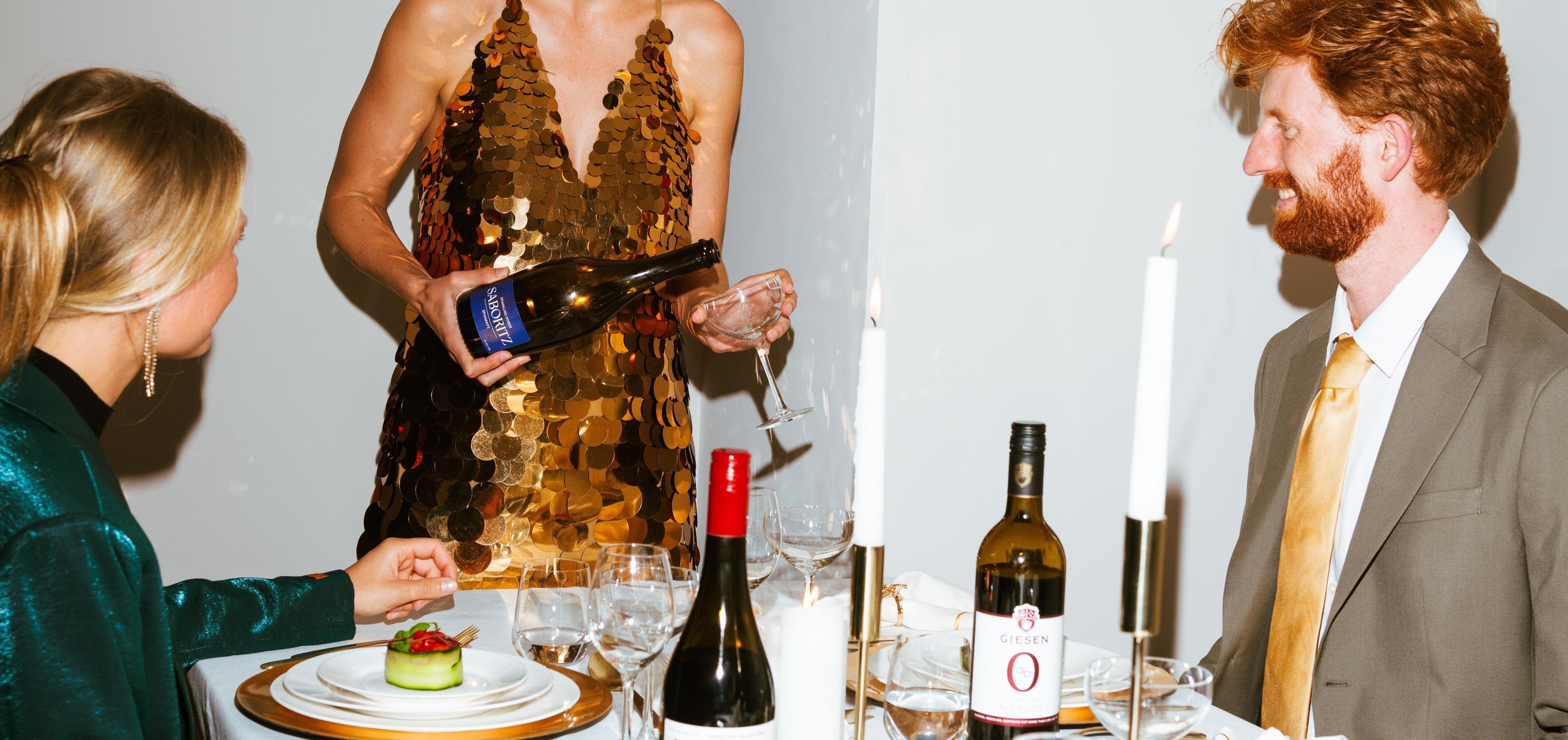 Feestelijk diner met mensen, alcoholvrije wijn en kaarsen aan gedekte tafel | World of NIX