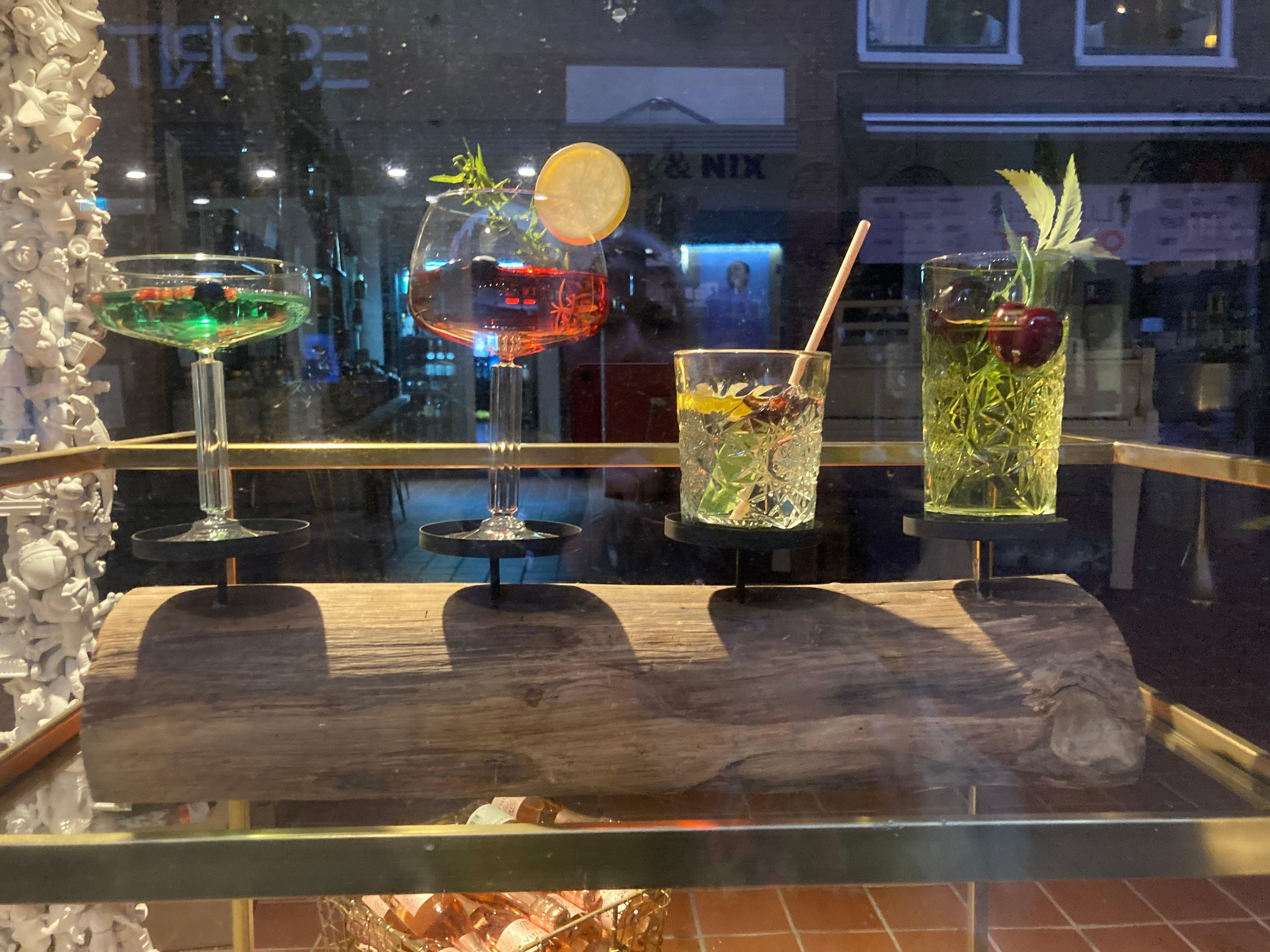 Vier kleurrijke alcoholvrije cocktails in glazen met fruit en kruiden op een houten plank | World of NIX