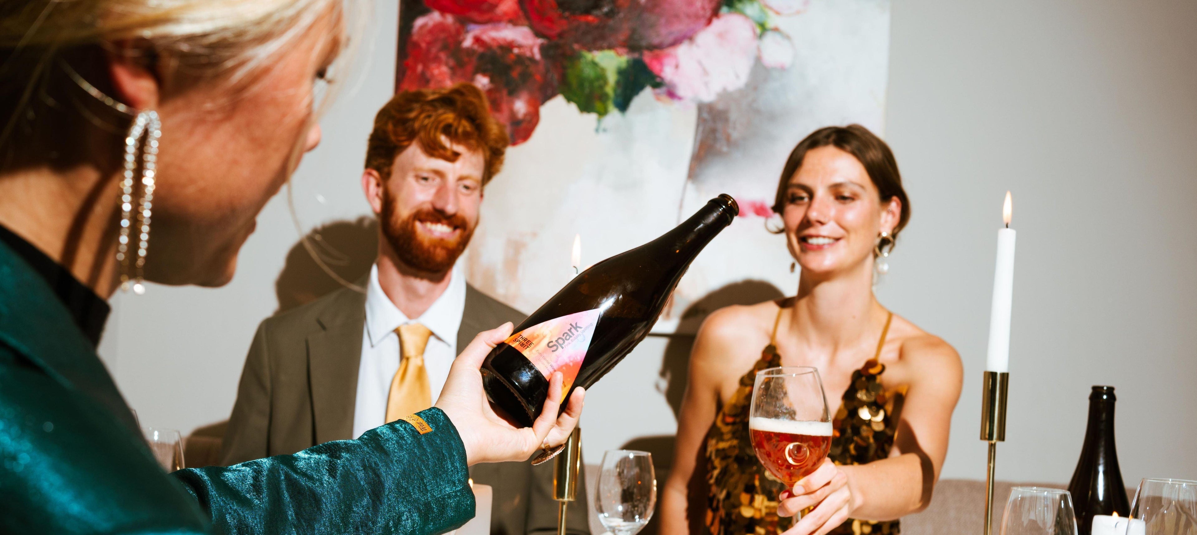 Drie mensen proosten met alcoholvrije sparkling tea aan een stijlvol gedekte tafel | World of NIX