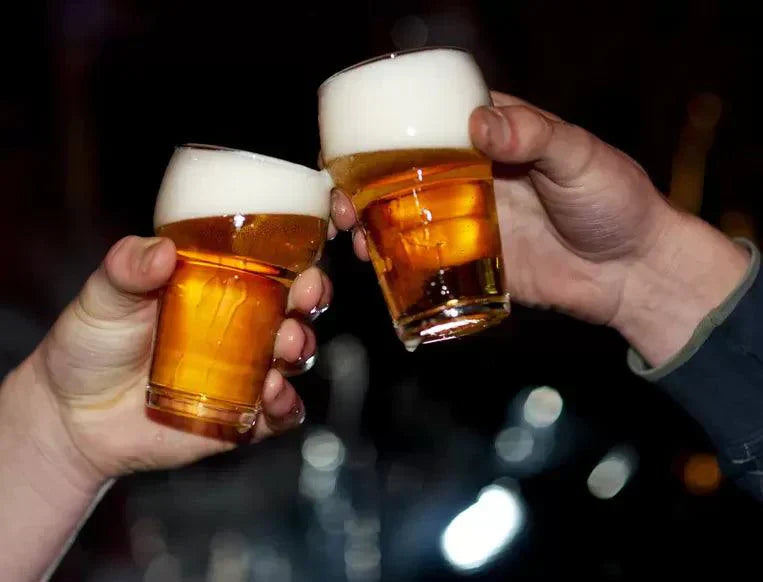 Twee handen proosten met glazen alcoholvrij bier, schuimkraag zichtbaar | World of NIX