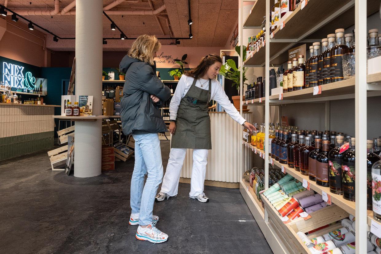 Medewerker helpt klant bij alcoholvrije spirits in moderne winkel | World of NIX