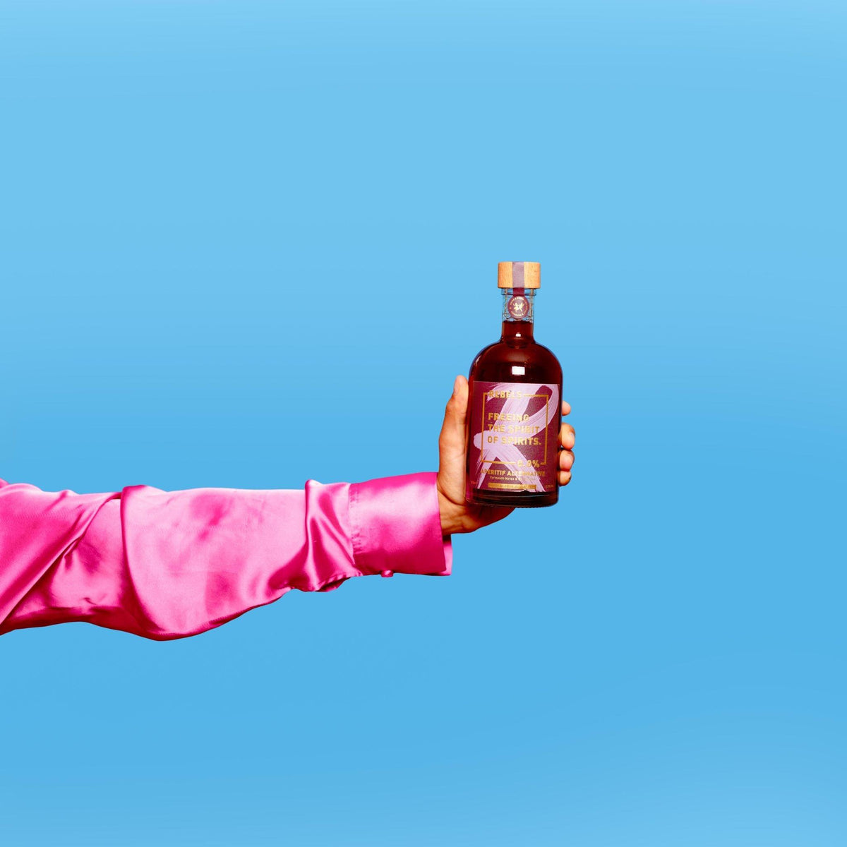 Hand met roze blouse houdt fles alcoholvrije spirit tegen blauwe achtergrond | World of NIX