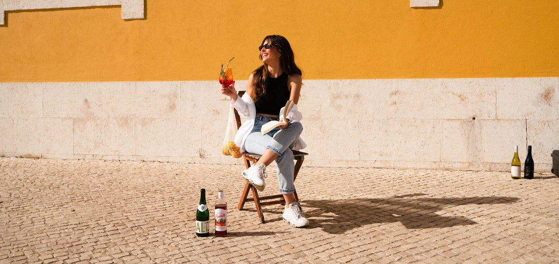 Vrouw geniet buiten van alcoholvrije drank, leest een boek, flessen 0.0 wijn en spirits erbij | World of NIX