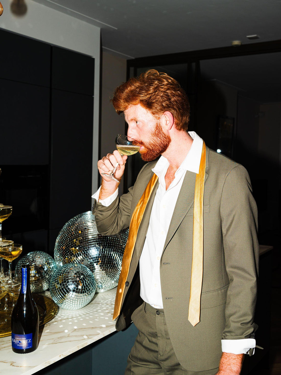 Man in pak drinkt alcoholvrije bubbels op feest, disco ballen en feestelijke setting | World of NIX
