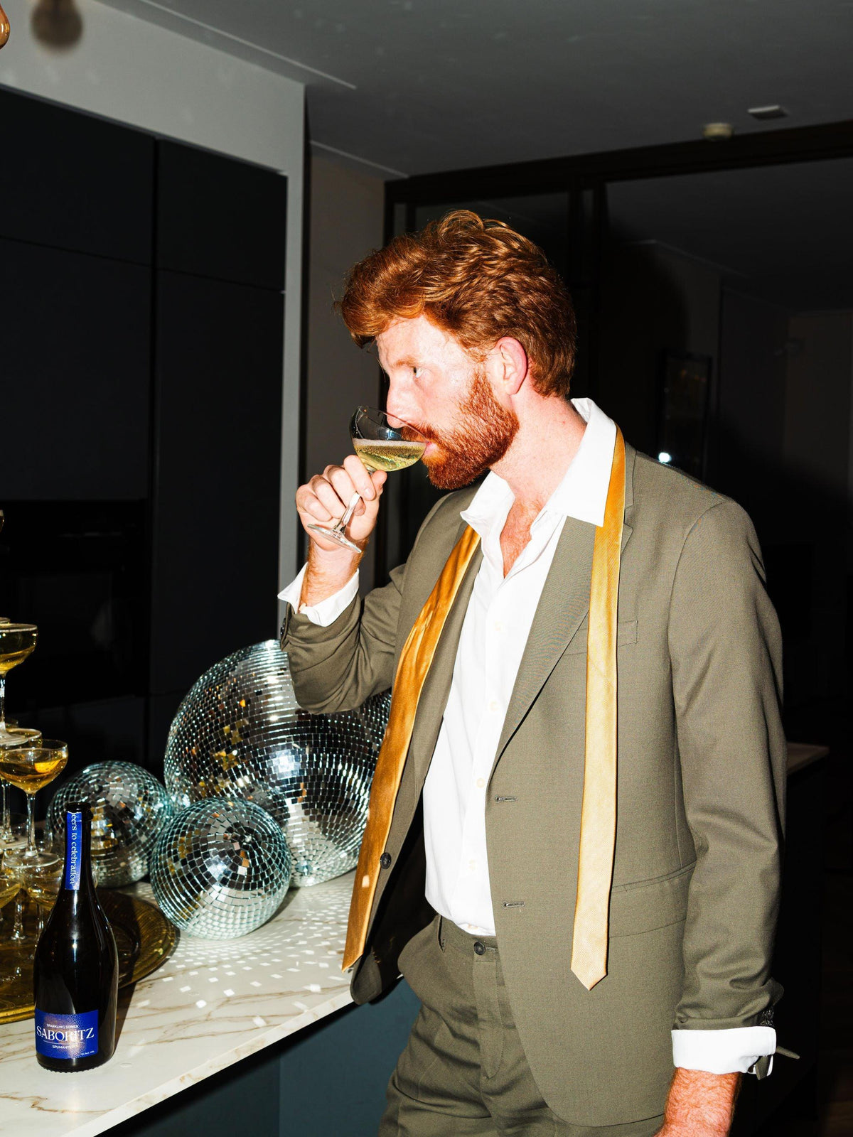Man in pak drinkt alcoholvrije bubbels op feest, disco ballen en feestelijke setting | World of NIX
