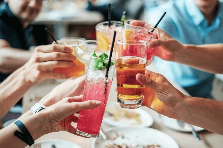 Groep mensen proost met kleurrijke alcoholvrije cocktails aan tafel | World of NIX