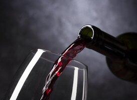 Rode alcoholvrije wijn wordt in wijnglas geschonken tegen donkere achtergrond | World of NIX
