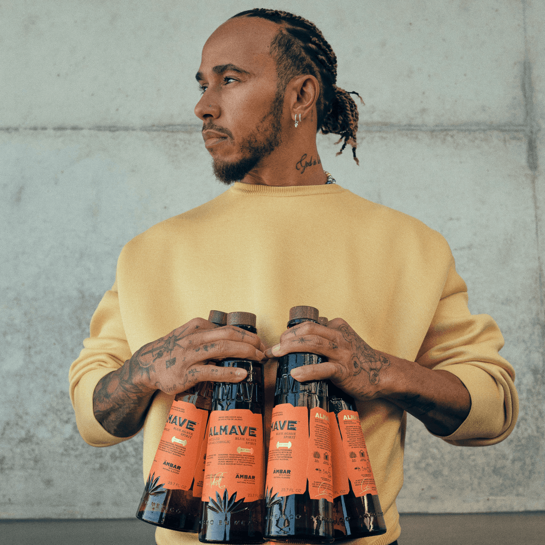 Man in gele trui houdt meerdere flessen Almave alcoholvrije tequila vast | World of NIX