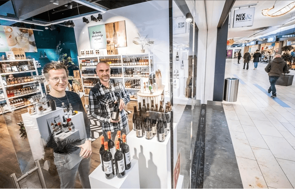 Twee mannen in een moderne winkel vol alcoholvrije wijnen en spirits, winkelcentrum | World of NIX