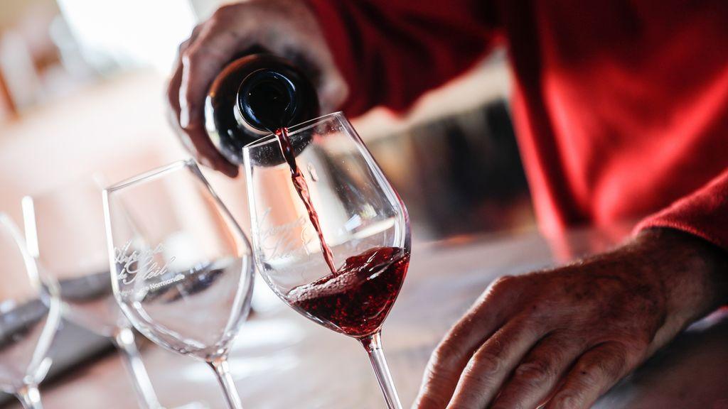 Hand schenkt rode alcoholvrije wijn in glas op houten tafel | World of NIX