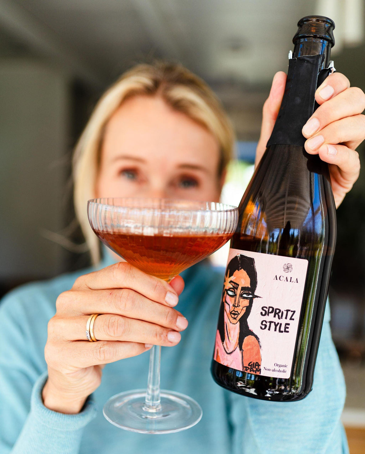 Vrouw houdt glas en fles Acala Spritz Style alcoholvrije sparkling tea vast | World of NIX
