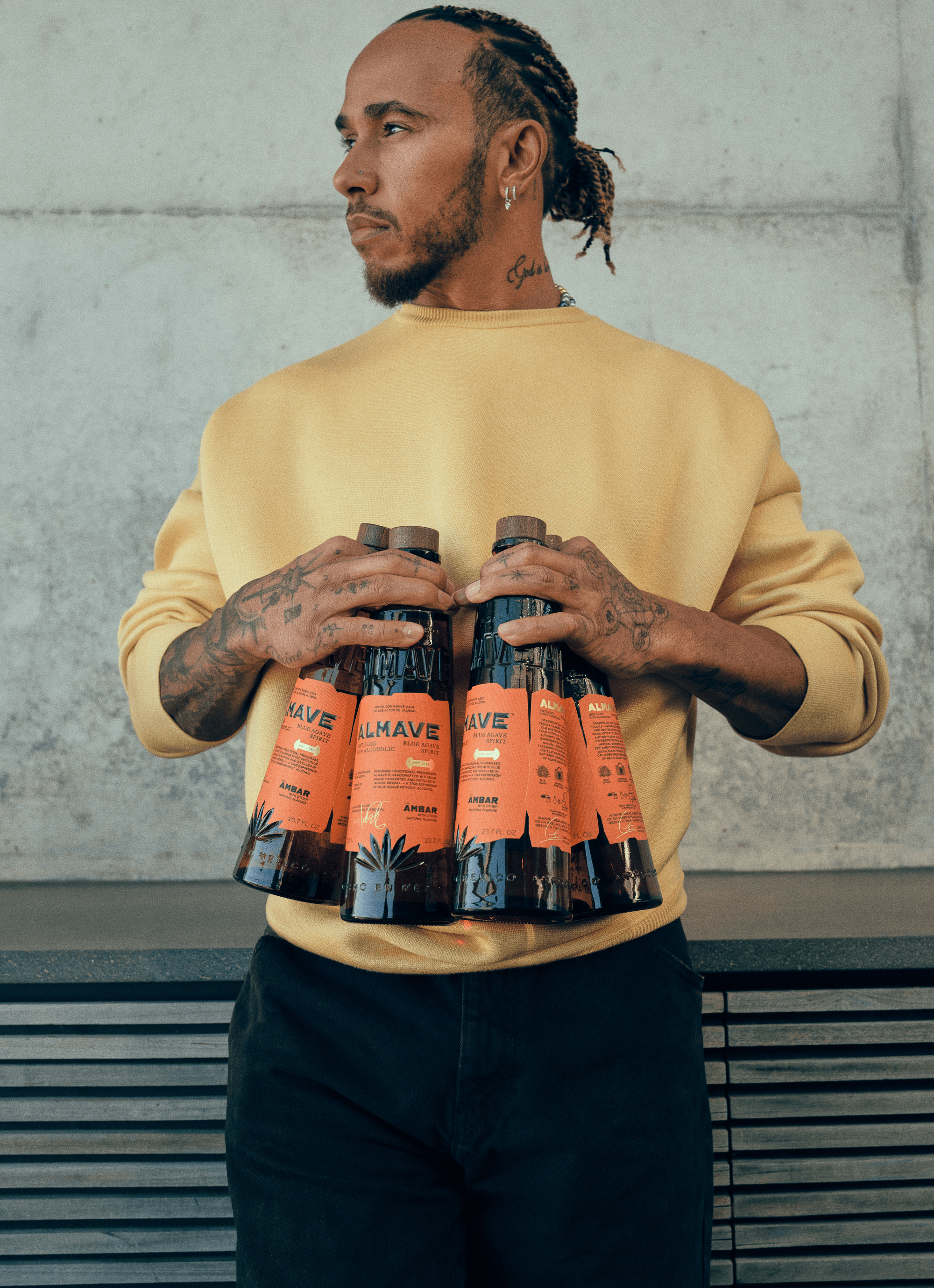 Man met gele trui houdt meerdere Ambar Almave alcoholvrije spirits flessen vast | World of NIX